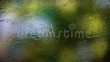 雨点从玻璃上落下来，绿叶树上的树枝在模糊的背景上摇曳